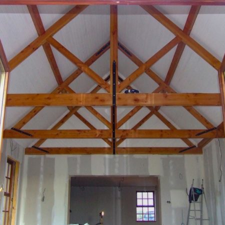 Multiple wooden roof trusses in a room being renovated