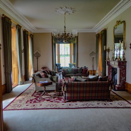 Large stately room showing sofa, chairs, fireplace and candles with large windows all round