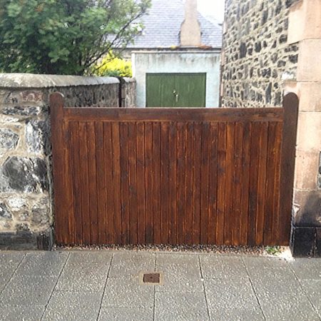 Large wooden gate between stone wall and stone building