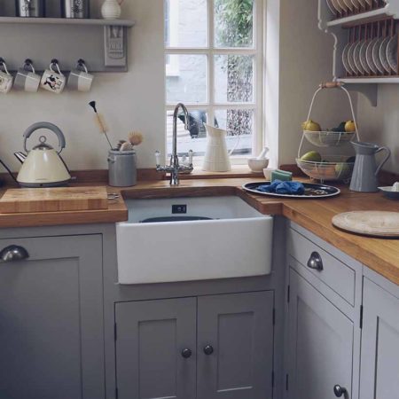 Grey wooden kitchen, Belfast sink and kitchen utilities and decor on workspaces
