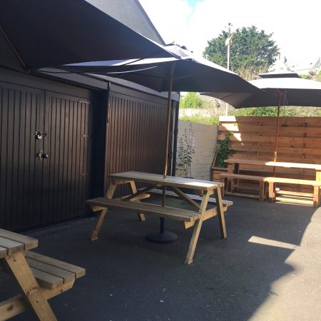 Three picnic benches with sun parasols in courtyard of Market Arms in Banff