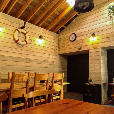 Inside of the Barn at the Market Arms showing wood panelled walls and dining tables and chairs