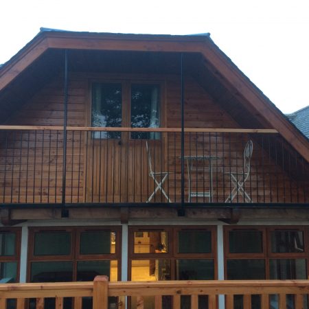 Wooden balcony with wooden door and wooden panelling, and bistro dining set