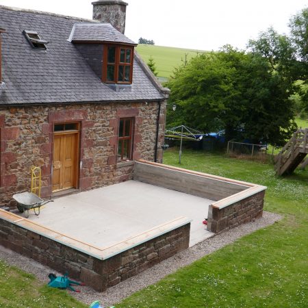 Two floor stone built house with newly constructed stone wall and cemented area to front of building